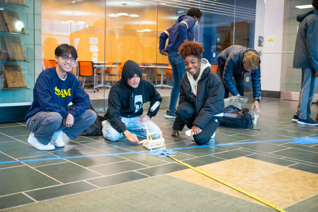 three students posing with their small car
