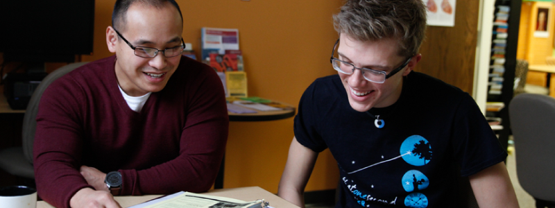 two students at a table smiling